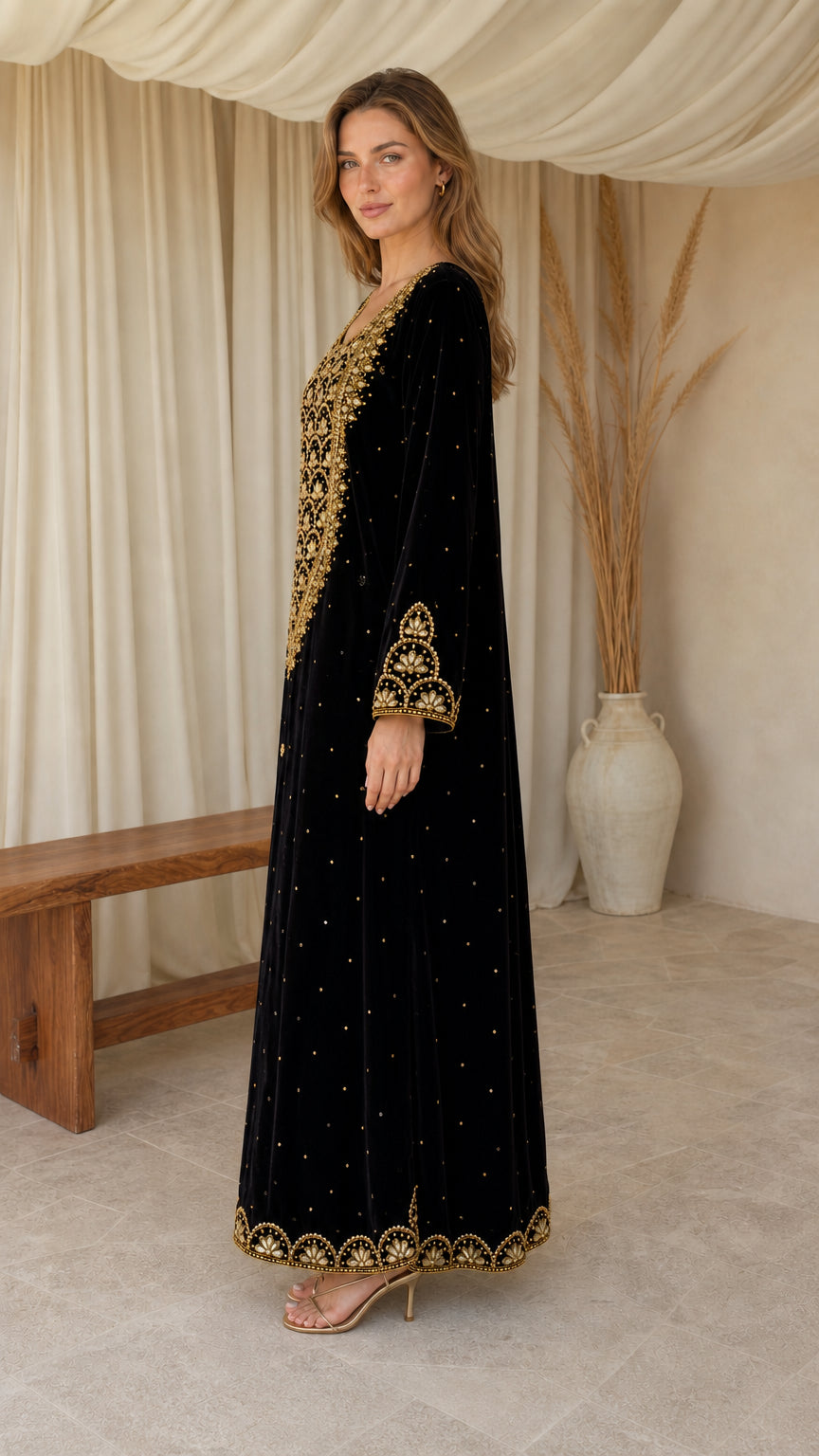 Model wearing black velvet kaftan dress with intricate gold embroidery - side angle