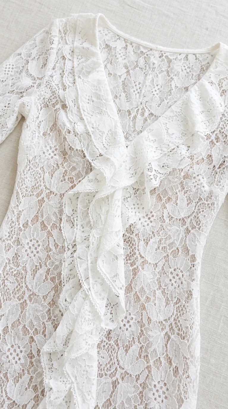 Close-up detail of white floral lace texture and neckline ruffles