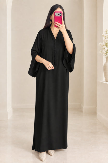 Front view of woman wearing black kaftan maxi dress with embroidered V-neck